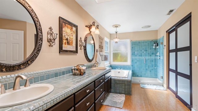 full bath featuring a stall shower, visible vents, a bath, a sink, and hardwood / wood-style flooring