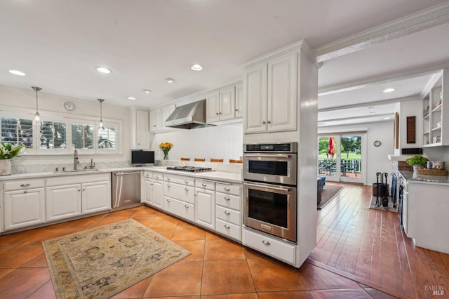 kitchen featuring white cabinets, a sink, stainless steel appliances, and wall chimney exhaust hood