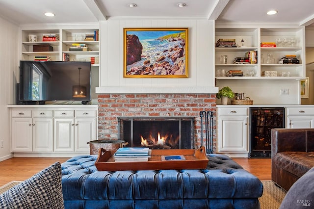 living room featuring crown molding, light wood-style floors, a brick fireplace, and beverage cooler