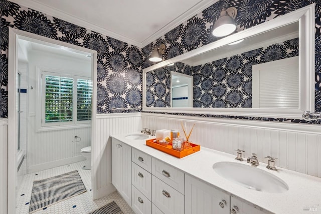 bathroom featuring wallpapered walls, a sink, a wainscoted wall, and toilet