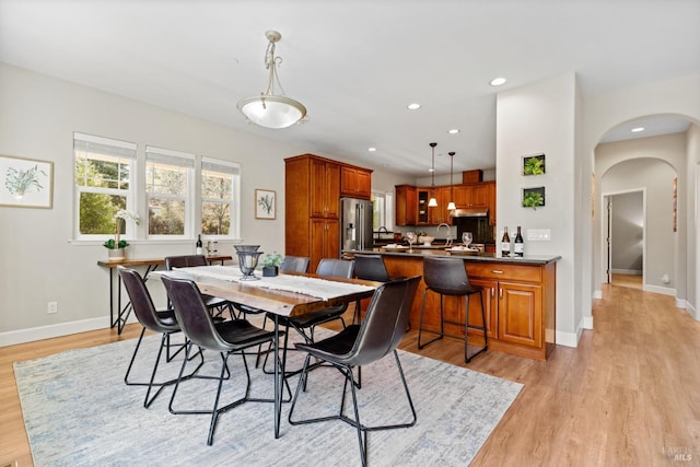 dining area featuring recessed lighting, arched walkways, baseboards, and light wood-type flooring
