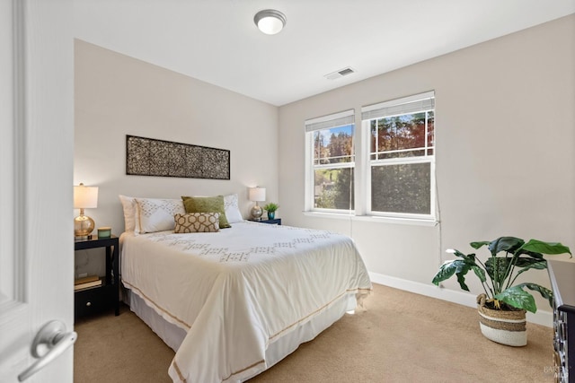bedroom featuring baseboards, visible vents, and light carpet