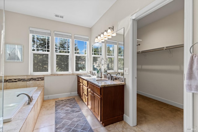 bathroom featuring a spacious closet, a sink, visible vents, double vanity, and a bath