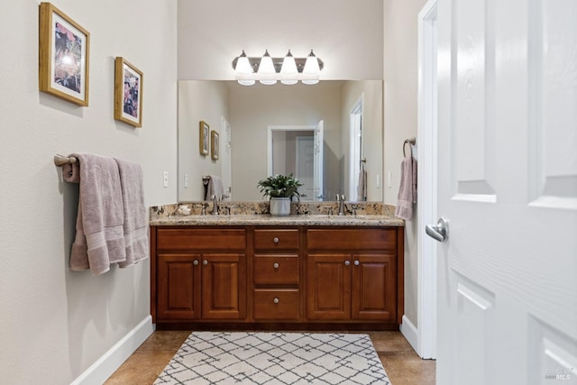 bathroom with tile patterned flooring, a sink, double vanity, and baseboards