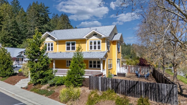 view of front of property with roof with shingles, covered porch, and fence private yard
