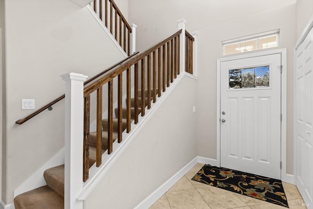 foyer with light tile patterned flooring, baseboards, and stairs