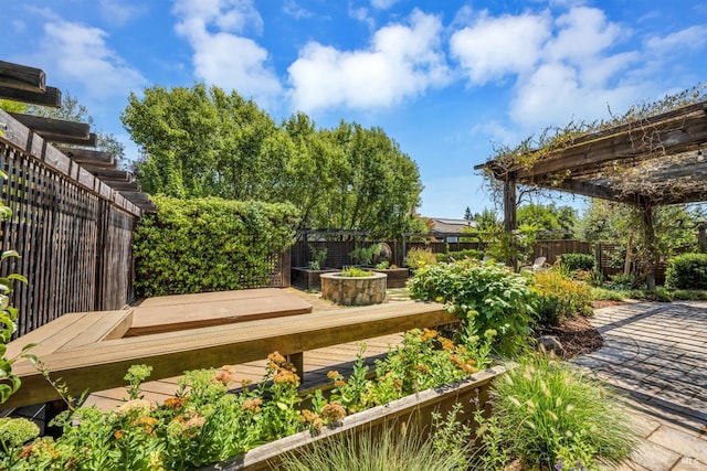 wooden terrace with a vegetable garden, a fenced backyard, and a pergola