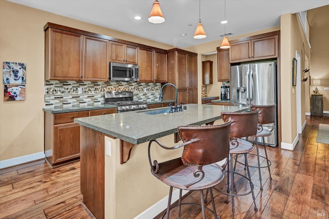 kitchen with backsplash, light wood-style flooring, a sink, and stainless steel appliances