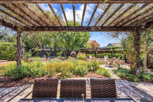 view of patio / terrace featuring a garden, an outdoor fire pit, fence, and a pergola