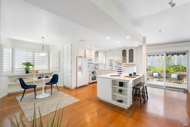 kitchen with light countertops, light wood finished floors, open shelves, and white appliances
