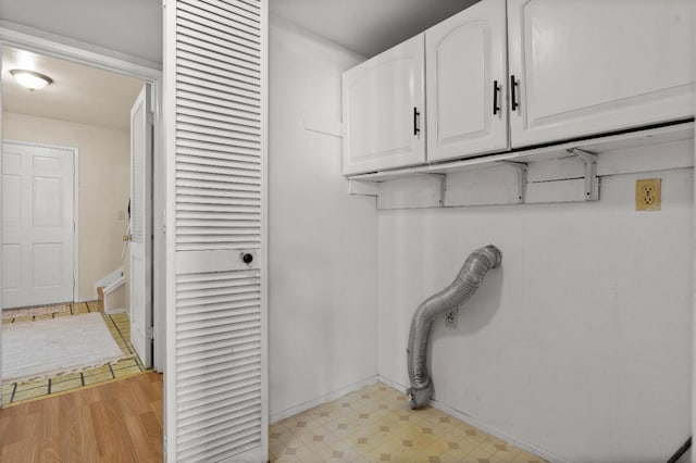 washroom featuring cabinet space, baseboards, and light floors
