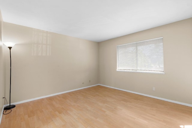 unfurnished room with baseboards and light wood-type flooring
