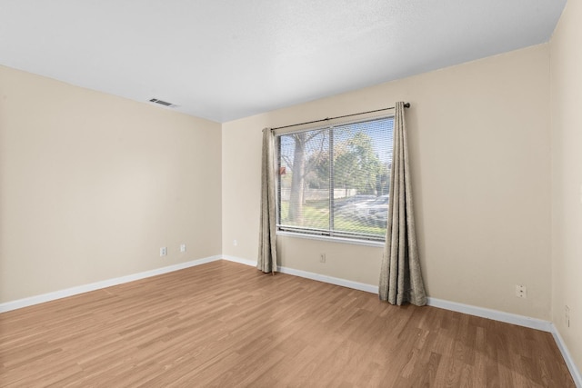 spare room featuring baseboards, light wood finished floors, and visible vents