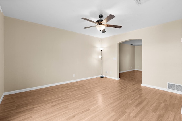 spare room featuring ceiling fan, visible vents, arched walkways, baseboards, and light wood-style floors