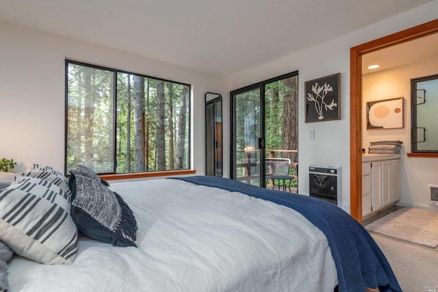 carpeted bedroom featuring heating unit, access to exterior, ensuite bath, baseboards, and recessed lighting