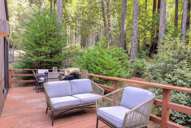 deck with grilling area, an outdoor hangout area, and a forest view