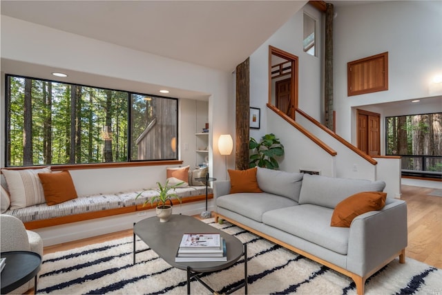 living area featuring high vaulted ceiling, stairs, and wood finished floors
