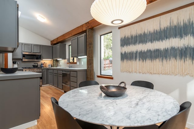 dining area with light wood-style flooring and vaulted ceiling