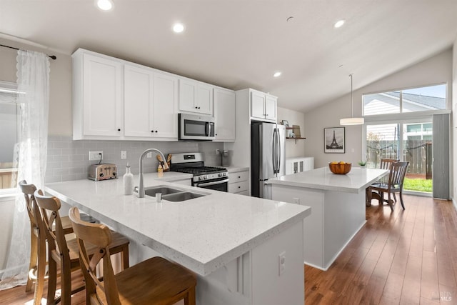 kitchen with a sink, stainless steel appliances, backsplash, lofted ceiling, and a kitchen island