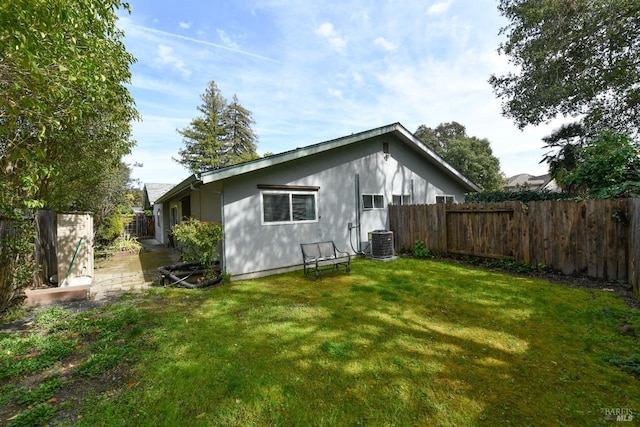 back of property with central AC, a yard, and a fenced backyard