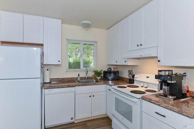kitchen featuring white appliances, under cabinet range hood, dark stone counters, a sink, and white cabinets