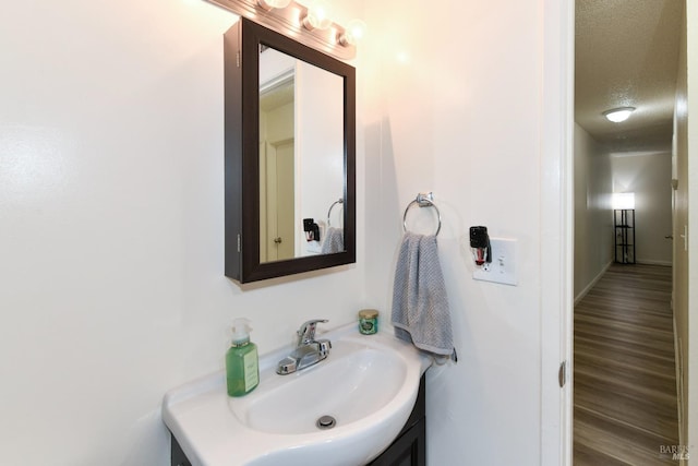 bathroom with a textured ceiling, wood finished floors, and vanity