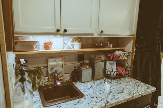 kitchen view of light stone countertops, white cabinets, and a sink