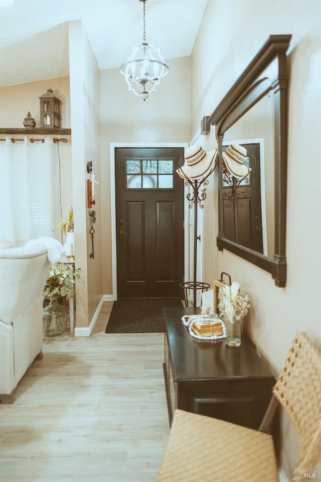 foyer with wood finished floors, a chandelier, and baseboards