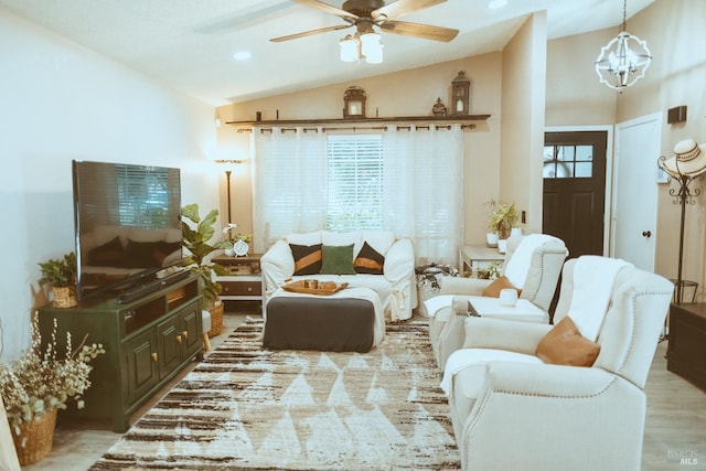 living room with vaulted ceiling, ceiling fan, a chandelier, and wood finished floors