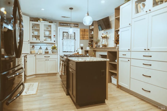 kitchen with freestanding refrigerator, open shelves, stainless steel range with gas stovetop, light wood-style flooring, and recessed lighting