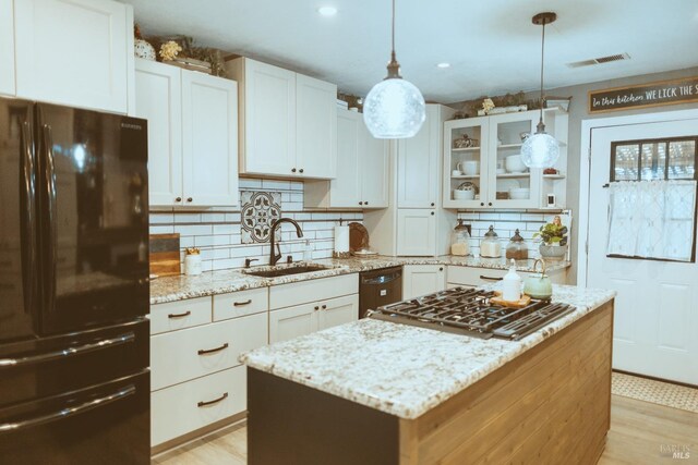 kitchen with freestanding refrigerator, a sink, stainless steel gas stovetop, backsplash, and a kitchen island