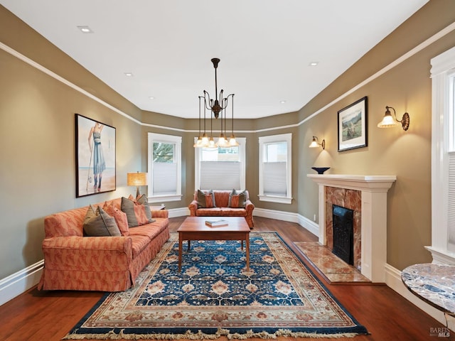 living room featuring baseboards, a high end fireplace, and wood finished floors