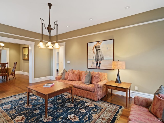 living room featuring baseboards, a notable chandelier, and wood finished floors