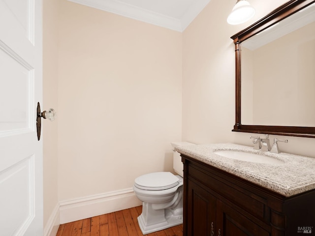 half bathroom featuring toilet, ornamental molding, hardwood / wood-style flooring, and vanity