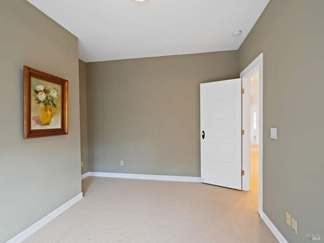 unfurnished room with baseboards and light colored carpet
