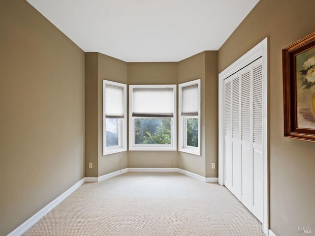 unfurnished bedroom with baseboards, a closet, and light carpet