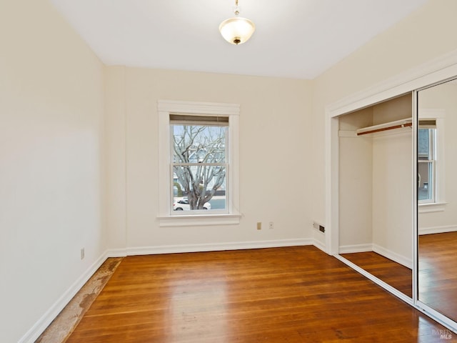 unfurnished bedroom with baseboards, wood finished floors, and a closet