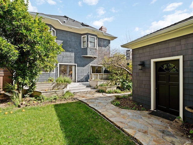 back of property with a yard and a chimney