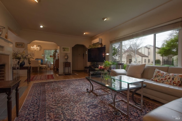 living room with wood finished floors, recessed lighting, arched walkways, an inviting chandelier, and an AC wall unit