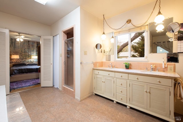 full bathroom featuring double vanity, a sink, a stall shower, and ceiling fan