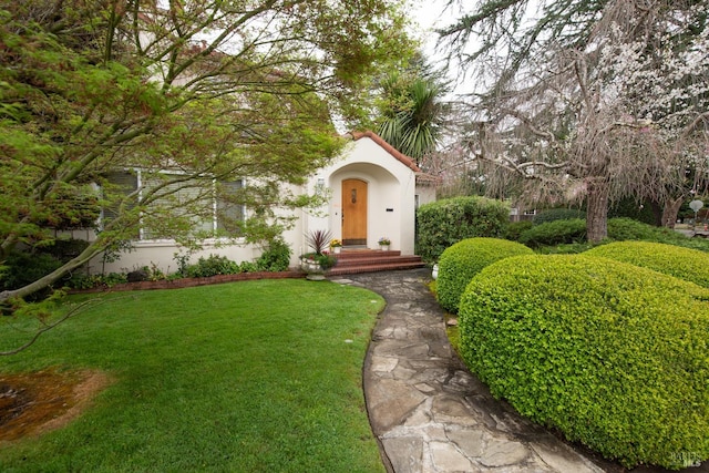 view of front of home featuring stucco siding, a tiled roof, and a front yard