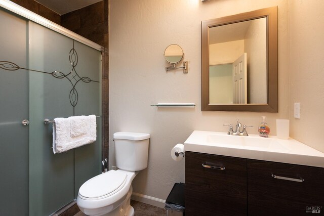 bathroom with a stall shower, baseboards, toilet, and vanity