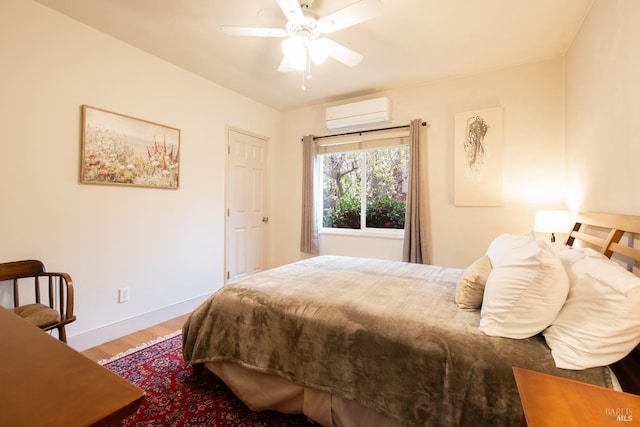 bedroom featuring baseboards, wood finished floors, a wall mounted air conditioner, and a ceiling fan