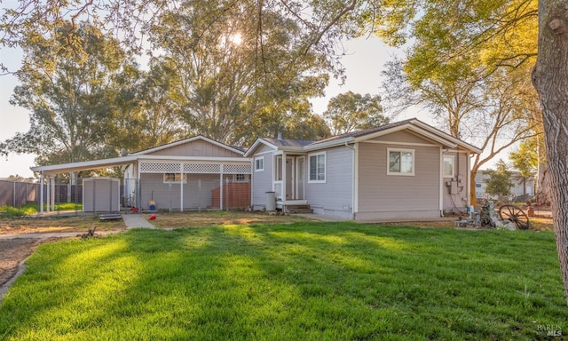 rear view of property with a lawn, entry steps, a carport, fence, and driveway