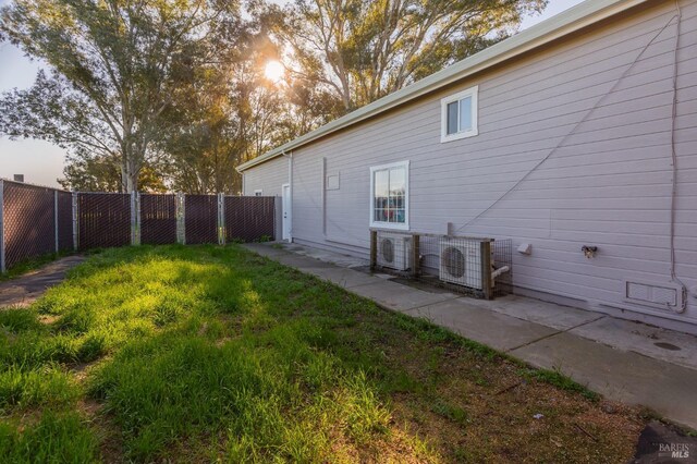 view of side of property featuring ac unit, a fenced backyard, and a lawn