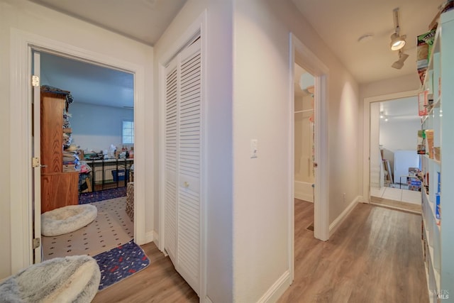 corridor with light wood-style floors and baseboards