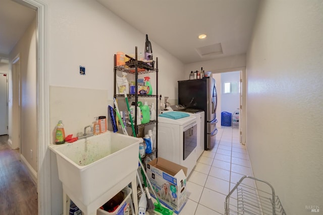 interior space with light tile patterned floors, attic access, washer and clothes dryer, laundry area, and a sink