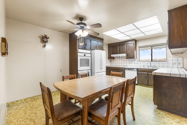 2062 Woolsey Rd, Fulton, CA 95439 - kitchen with dark brown cabinetry, white appliances, under cabinet range hood, light floors, and tile countertops