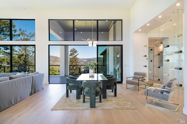 dining area with a towering ceiling, recessed lighting, and wood finished floors