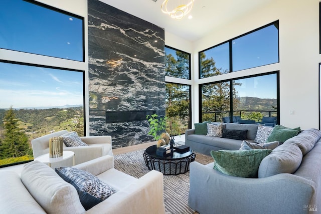 living room featuring plenty of natural light, a notable chandelier, a mountain view, and a towering ceiling
